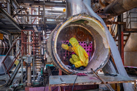 Male workers use high-pressure water jets to clean splashing the dirt of tube boilers in industrial areas or toxic hazardous material