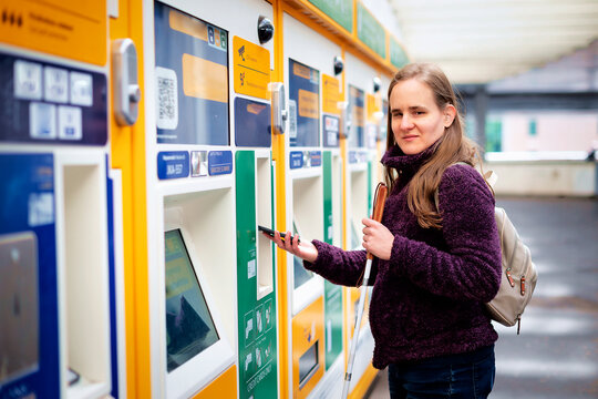 Visually impaired woman standing on the train station and buying ticket