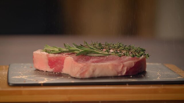 fresh cut raw steak with rosemary on dinner table