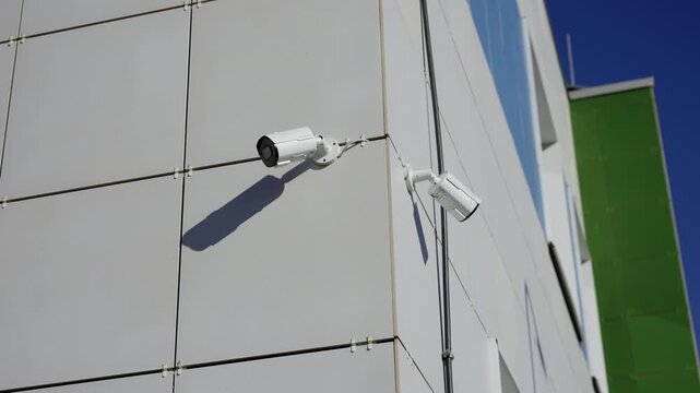 Surveillance camera overlooks entrance area of contemporary building. Simple exterior design and safety systems create organized workspace