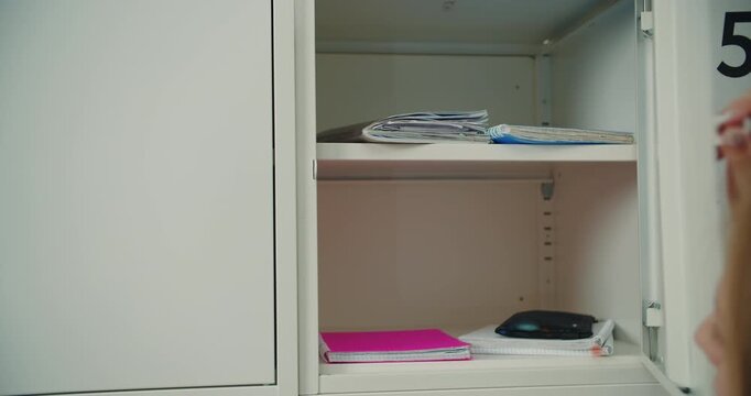 Schoolgirl opening locker with key at school