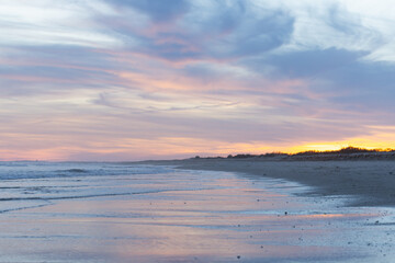 Fototapeta premium Gentle waves and a glowing sky in shades of pink and blue create a serene atmosphere
