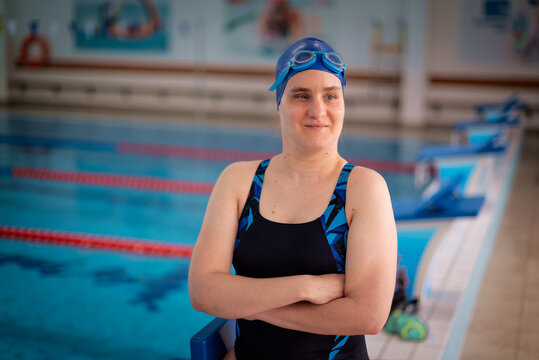 Visually impaired woman in swimsuit standing by the indoor swimming pool