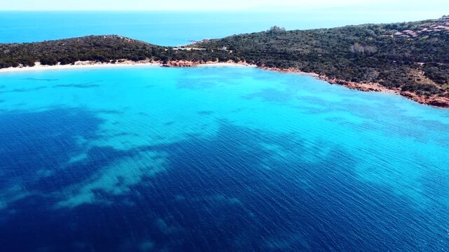 Aerial pull back view of Capo Coda Cavallo with deep blue sea rocky coastline and Mediterranean landscape in Sardinia on a sunny day