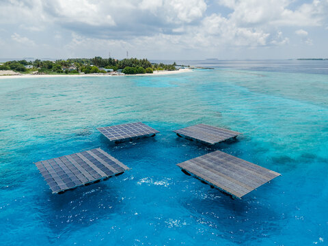 Aerial view of the SolarSea floating solar power plant platforms on turquoise waters near the tropical island of Dharavandhoo, Baa Atoll, Maldives.