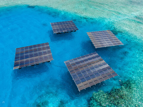 Aerial view of SolarSea floating solar power plant platforms on turquoise water over a coral reef in Dharavandhoo, Baa Atoll, Maldives.