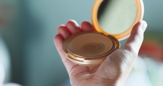 Woman applying powder with a puff from a compact case, soft lighting, beauty and skincare routine concept, minimal and elegant daily makeup moment, Close-up