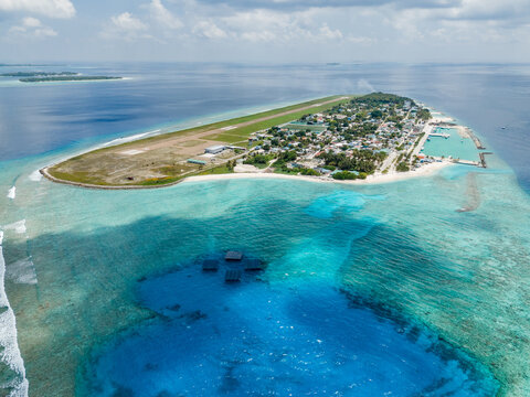 Aerial view of SolarSea floating solar power plant by Swimsol near the island featuring the airport runway and turquoise lagoon Dharavandhoo, Baa Atoll, Maldives.