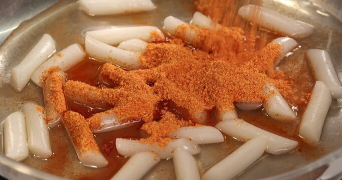 Process of cooking the Korean national dish tteokbokki. Red dry sauce powder is added to tteokbokki in a dry sauce powder.