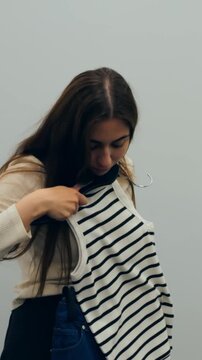 Playful woman showcasing outfit. Charming woman in changing space with lively fashionable stance. Elegant female model exhibits trendy clothing with cheerful demeanor in dressing room setting