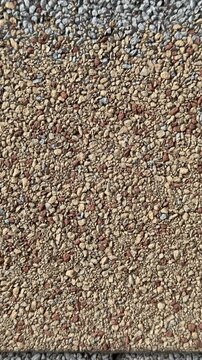 Close-up cottage roof tiles showing granular texture, rough mineral granules, dark vertical seam lines, offset tile arrangement