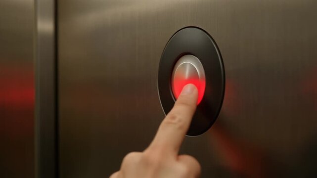 Finger pressing elevator button with red light.