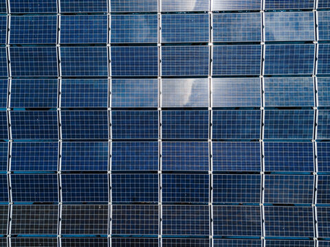 Aerial view of the SolarSea floating solar power plant with a grid of blue photovoltaic panels reflecting the sky in Dharavandhoo, Baa Atoll, Maldives.