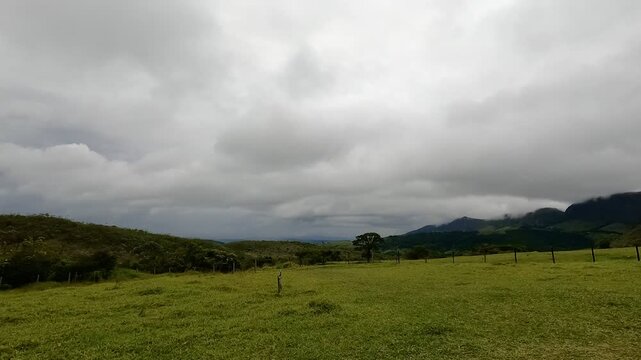 Cloudy Sky Over Green Hills and Meadows in Rural Countryside Landscape