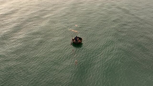Vietnamese Fishermen in Traditional Thung chai Boat. The Sea near Da Nang city in Vietnam, Aerial Sunrise Drone Shot.