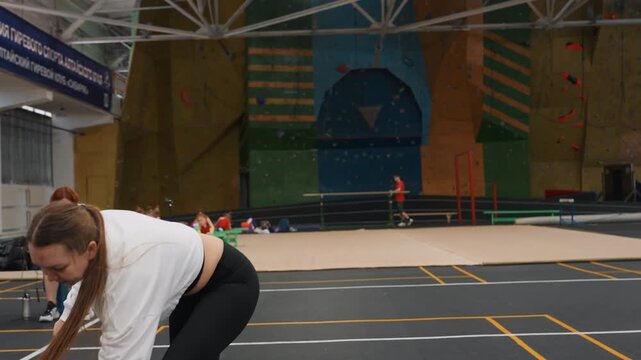 White woman playing badminton with energy, lively footwork drills and racket swings, smash and drop attempts, indoor sports hall atmosphere, upbeat rhythm and casual teammates in background, confident
