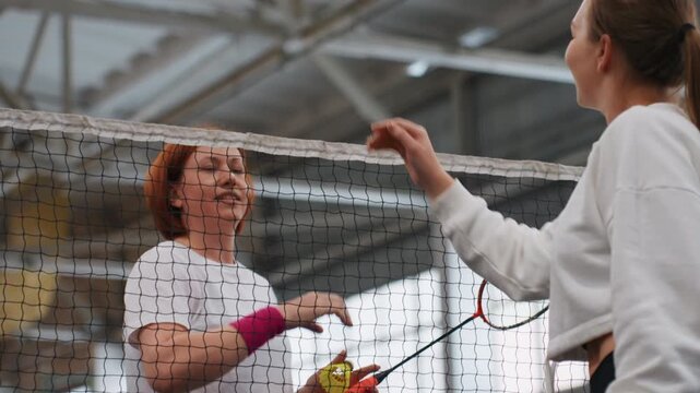 Indoor badminton rally white player celebrating highfive with partner on court, smiling exchange, point celebration, casual club atmosphere, racket motion, shuttlecock release, friendly energy