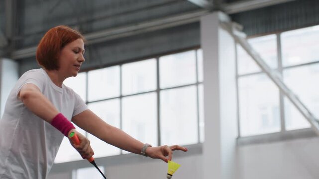 Indoor badminton practice white player executing powerful smashes and precise drives, intense footwork, concentrated expression, wristband accent, bright gym windows, focused training