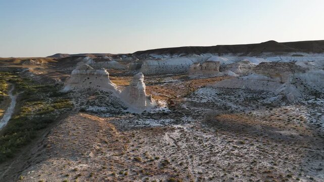 Drone takeoff over bizarre white chalk outcrops and dry desert hills. Footage showcases the unique, alien-like landscape of the Mangystau region, Kazakhstan. A grand view of the ancient Tethys 