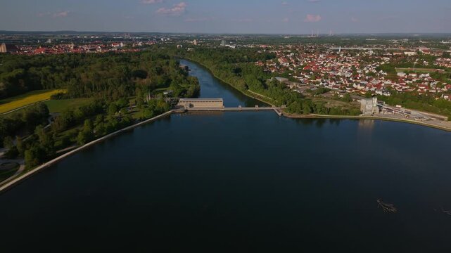 Aerial footage shows the Ingolstadt reservoir with blue water, natural land strips and the hydropower facility. Sunny weather highlights the Danube basin and surrounding recreation areas.