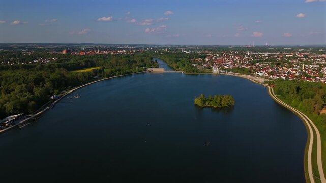 The Ingolstadt reservoir and Donau dam appear from above with clear summer light, blue water, Vogelinsel and the Laufwasserkraftwerk Ingolstadt set in a wide Bavarian panorama.