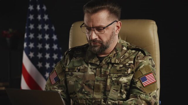 U.S. military officer in his 50s working on operational planning using laptop