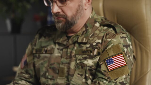 American intelligence officer working on laptop in office, preparing reports