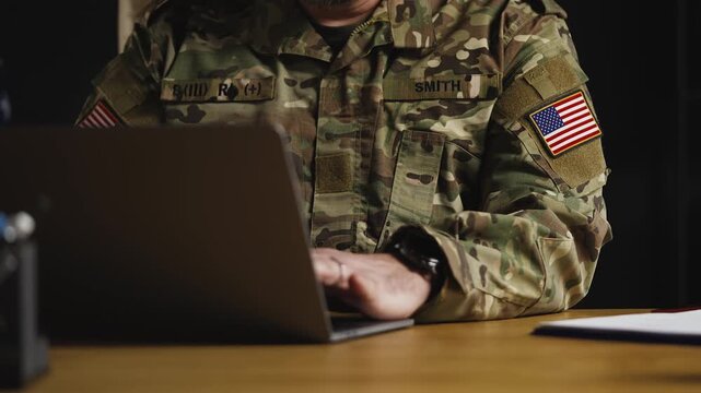 American army general typing on laptop in office, planning defense operations