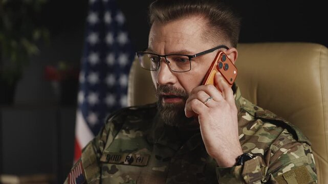 Middle-aged serviceman in eyeglasses coordinating mission via phone and laptop