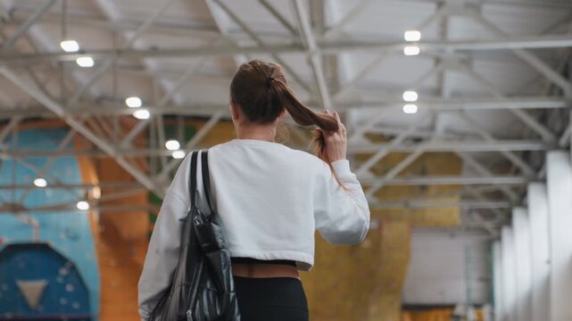 Woman with braided hair evaluates court. Female player checks badminton court setup before game starts. Urban sports setting features woman with braided hair preparing for sporting event