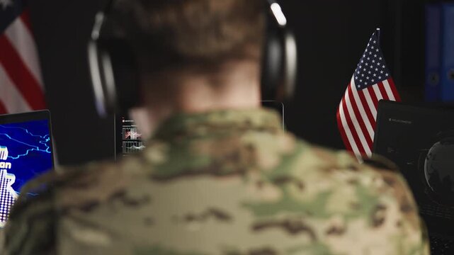 American soldier in headset controlling military operation in Iran on laptops