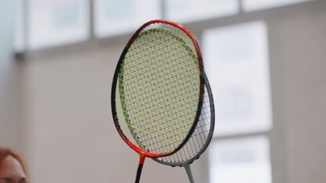 Closeup badminton racket in indoor gym, coach demonstrating grip technique with focused slowmotion frames, soft window light, neutral background, equipment detail and shuttlecock anticipation,