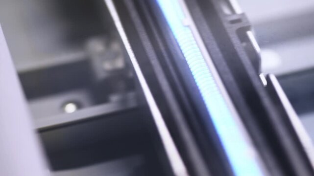 Close up details of flatbed scanner interior with illuminated scanning light and metallic components