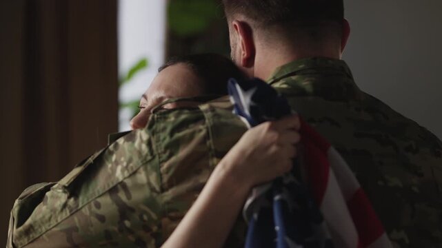 American woman embracing her soldier husband coming back home, family reunion