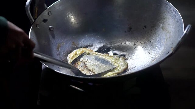 Cooking an egg in a hot pan as a complement to delicious and simple homemade fried rice.	
