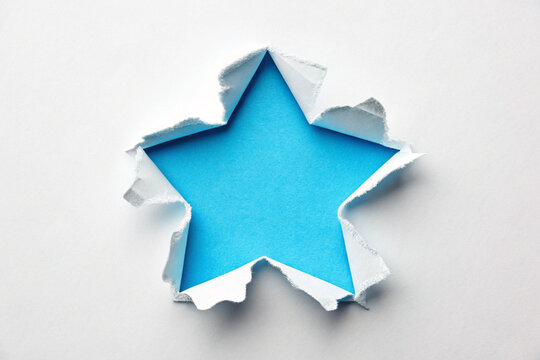 Star shape torn paper hole on blue background, ripped paper frame with rough edges, creative design element