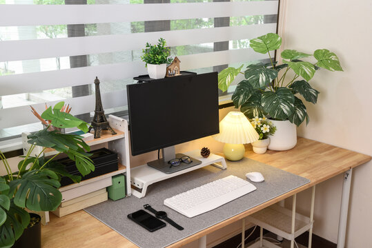 Modern contemporary home office setup with wooden desk surrounded by green plant