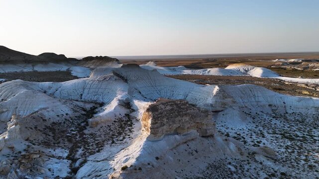 Close-up drone view of bizarre white chalk rocks and outcrops in the Mangystau desert. A detailed look at the textures of ancient geological formations and dry hills in Kazakhstan. Footage highlights 