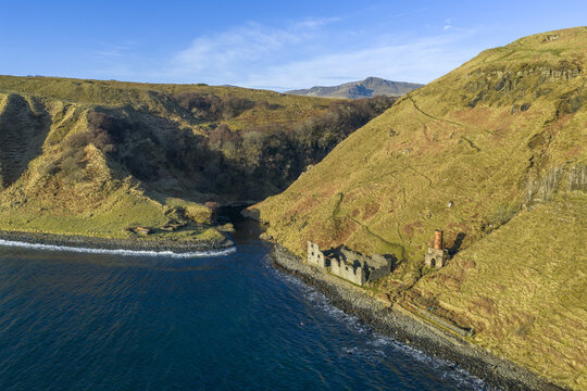 Aerial view of the historic ruins at Lealt Falls along the rugged coastline with steep grassy cliffs and blue sea Isle of Skye, Scotland, United Kingdom.