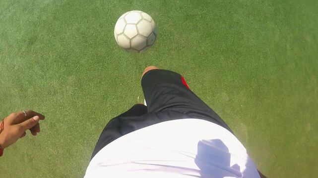 Football player skillfully dribbling ball on green turf, showcasing dynamic footwork and control, with shadows enhancing the action and emphasizing movement in a vibrant scene