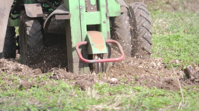 A stump grinder grinds down a tree stump in the soil.