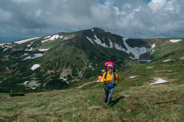 Fototapeta premium Female backpacker hiking near Lake Brebeneskul in the Carpathian Mountains through a dramatic alpine landscape. Adventure travel and wilderness trekking concept. Copy, empty space for text