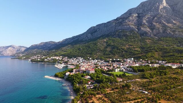 Aerial view of a coastal town in Croatia with the Biokovo mountain range in the background and the blue Adriatic Sea