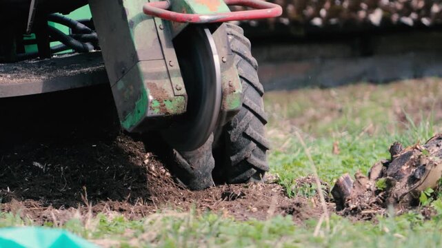 A stump grinder grinds down a tree stump in the soil.