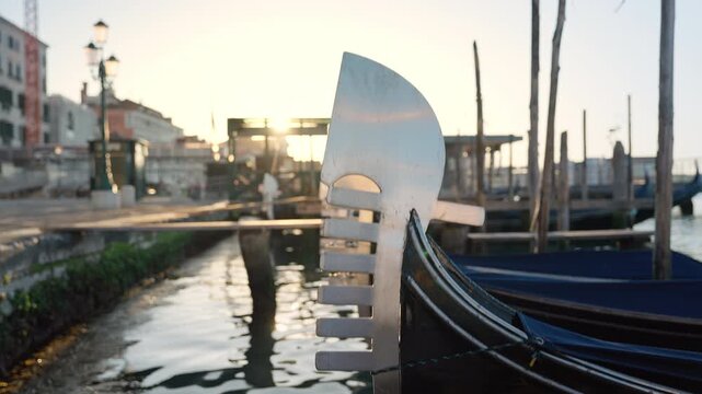 Venetian gondolas with ferro ornament moored, floating on calm morning water