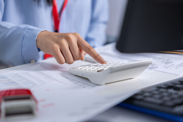 Fototapeta premium Focused business employee hand typing on calculator at office desk analyzing finance accounting document and paperwork for corporate tax budget calculation