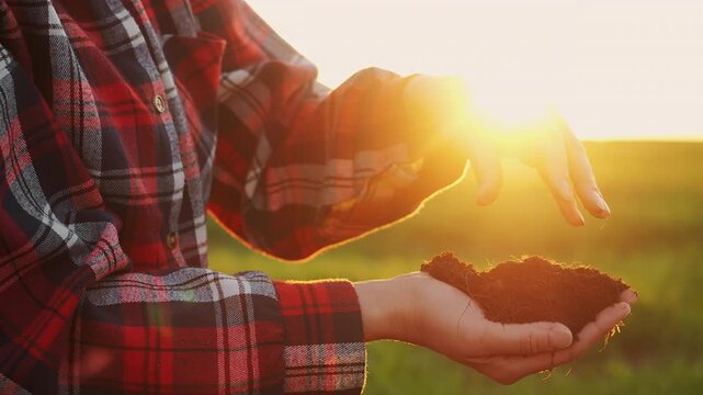 Close up of farmer hands checking fertile soil in agricultural field at sunset during golden hour outdoors.