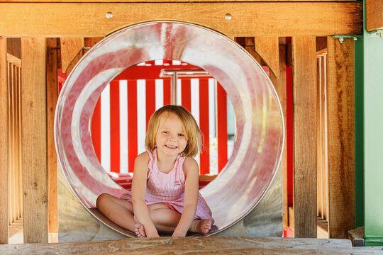 Happy child girl on playground. Kids play outdoor.