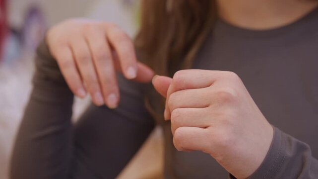 Closeup white woman hands wiping flakes, using tissue to remove dry skin and debris, gentle grooming motion, preparing nails for manicure, warm indoor lighting, intimate personal care scene scenario