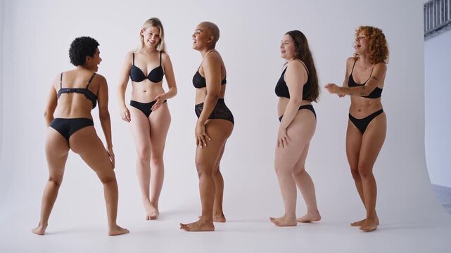 Multiethnic group of women wearing underwear with diverse kind of bodies. Young women having fun in a studio , posing in lingerie and feeling good in their body.
